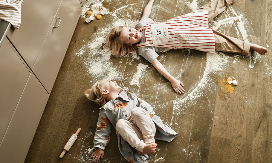 kids messing around in flour and eggs on a brown parquet floor